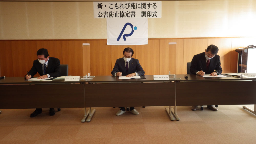 3名が座って公害防止協定書に調印をしている様子