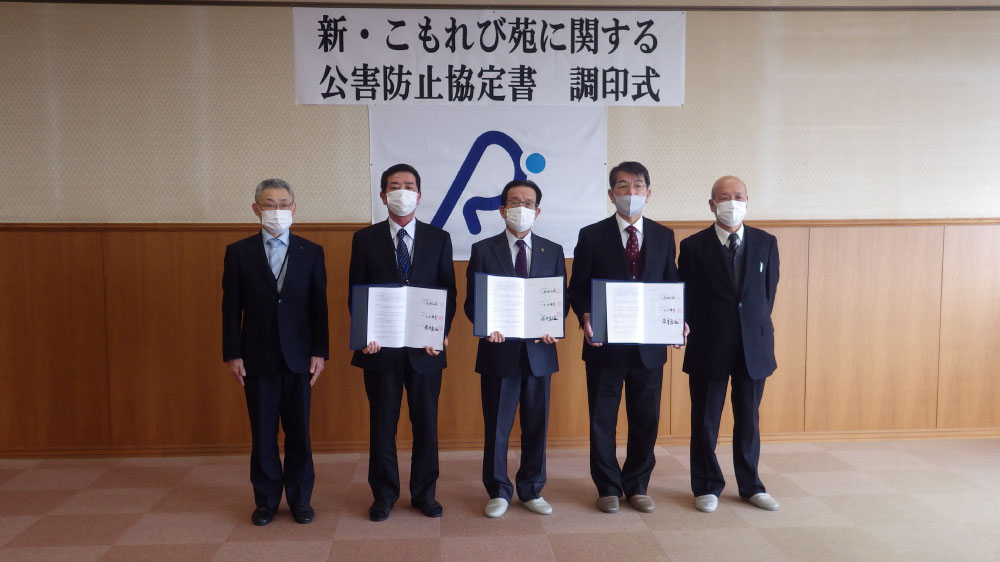 公害防止協定書を手に5名が並んで立っている様子