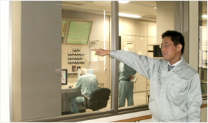 中央制御室を指さしている男性職員の写真