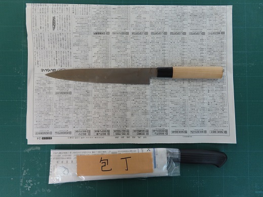 新聞紙の上に置かれた包丁と、新聞紙で包んで「包丁」と書かれたガムテープを貼った包丁の写真。